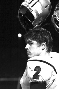 Raising his helmet into the air toward the end of the game, senior Aaron Ramsey stands along the sidelines with the team during the varsity game against Blue Valley West. Photo by Anna Glennon.