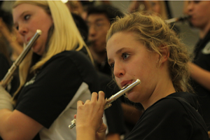 Focused on the drum major, sophomore Abbigayle Caldwell plays along with the band as they practice the National Anthem before the students enter the gym for the fall sports assembly. 