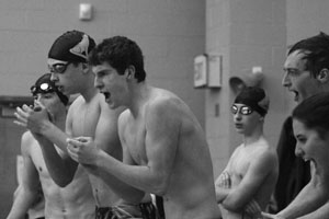 As their teammate pushes through his race, sophomore Bradon Spitler yells along with other swimmers to encourage the team. Photo by Anna Glennon.