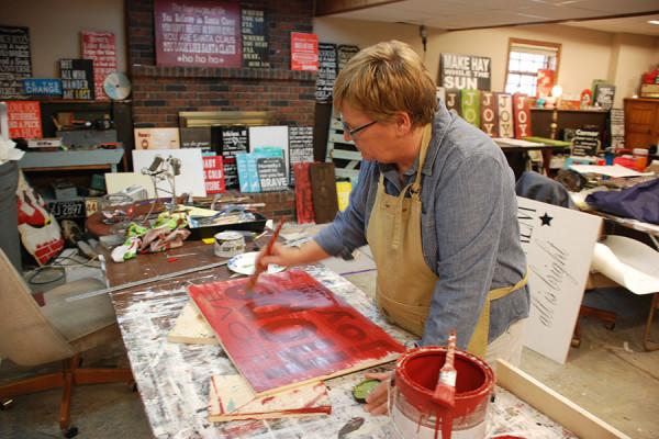Leanne paints one of her signs in her workshop. 