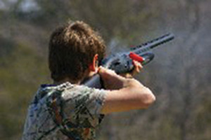 Noah fires his shotgun at a clay target.