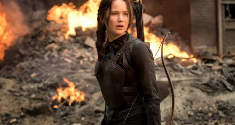 Katniss  stands in front of a burning building after a battle with Capitol fighters. 