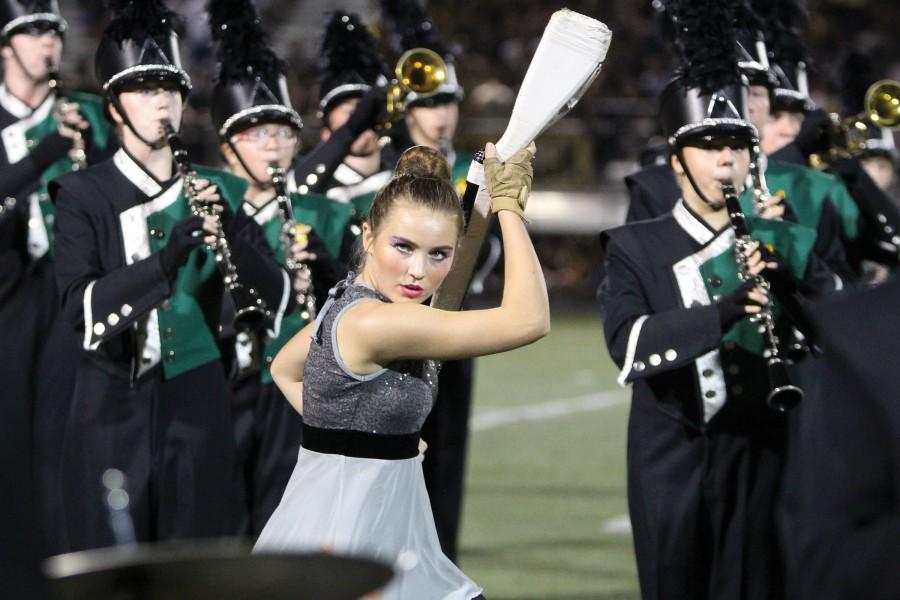 Twirling her rifle, sophomore Claire Boomer performs in the halftime show at the football game on Sept 25. Boomer is a part of the Color Guard, which performs and competes with the band. 