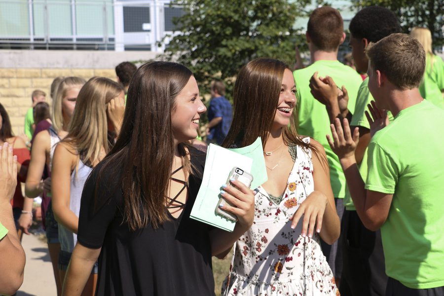 Freshman students walk through the courtyard while mentors and staff clap for them.