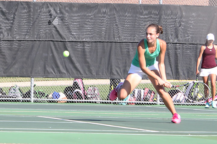 Swinging her racquet, senior Josie Henzlik runs to the ball.