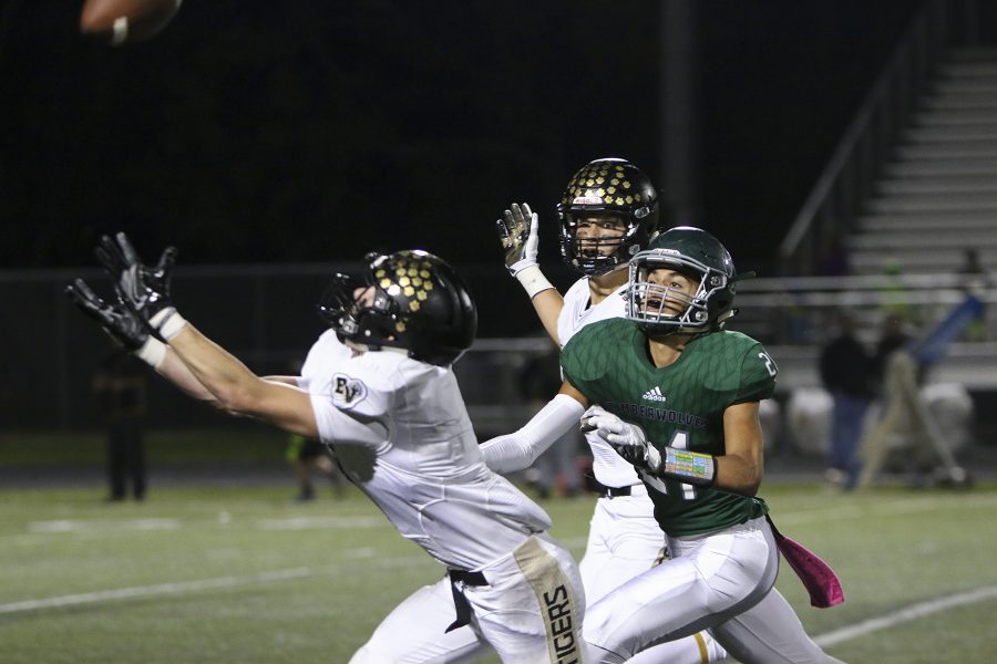 Chasing after a Blue Valley High opponent, number 21 senior Daniel Foulon aims to catch the ball to prevent an interception during the fourth quarter. 