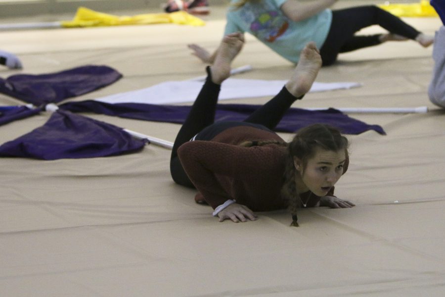 Doing floor work, junior Claire Boomer rolls and looks ahead to watch her fellow winter guard members. 