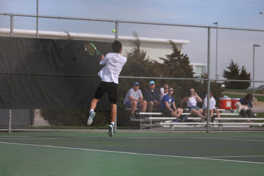 With a jump senior Ted Shi back hands the ball to the other court