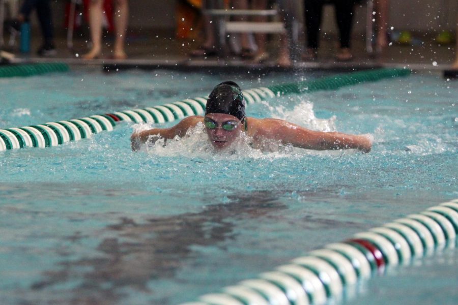 Pulling her arms around, junior Emerson Ralston comes up for air while swimming butterfly. 