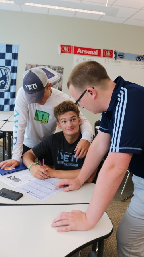 During Timber Time, Spanish teacher RJ Palmgren helps junior Tanner Curry with a vocabulary assignment, while senior Drew Jennings offers support.