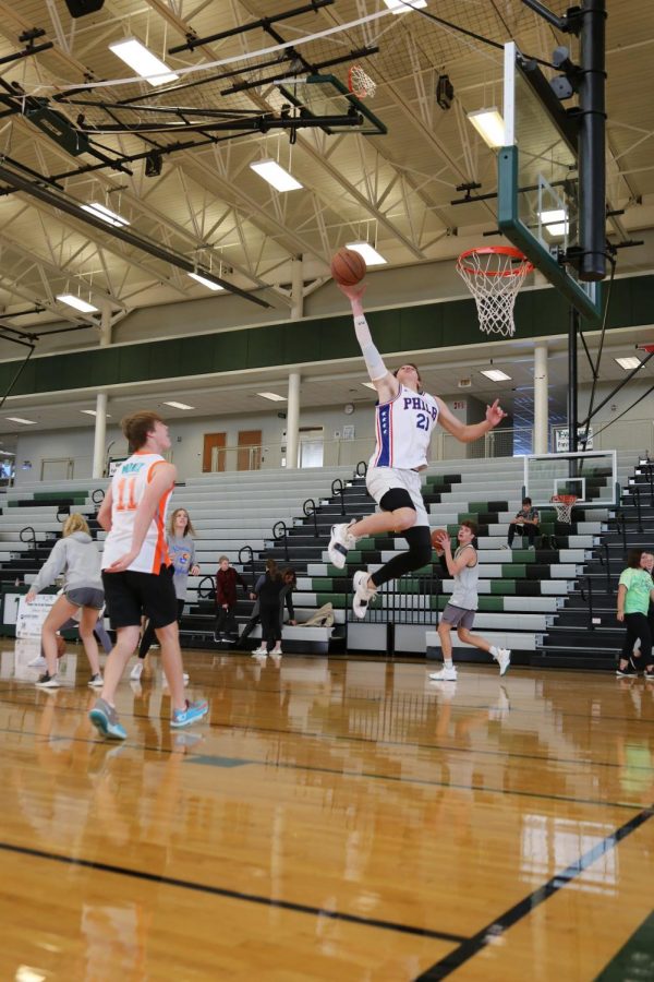 While warming up for the competitive game, junior Benjamin Kudrna dunks the basketball.