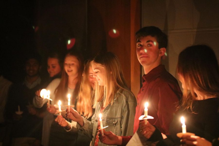 Illuminated by her candles light, junior Katelyn Seyl smiles at the NHS induction ceremony.