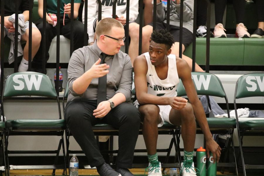 Assistant boys varsity coach RJ Palmgren talks to Senior KaLon Hale on the sideline.