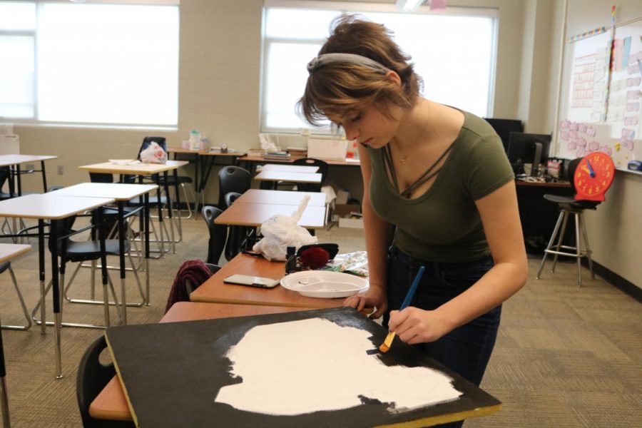 Junior Olivia Palmer fills in the background of her painting of China.