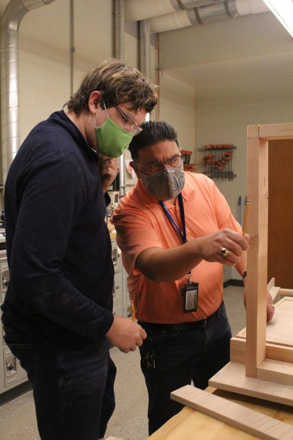 Teacher Steven Cortez helps junior Jackson McCarty add the finishing details to his desk.