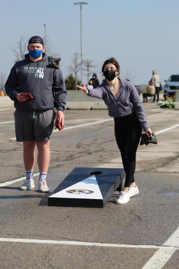 Two bags in hand, senior Lily Spinner throws one of her cornhole bags at Cornhole for a Cure on April 24, 2021. With the COVID-19 restrictions, Cornhole for a Cure was made as a replacement event for Hoops 4 Hope. 