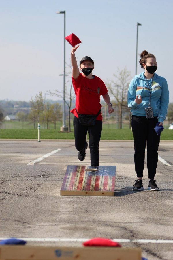 Foot in the air, senior Olivia Parsons lets go of her cornhole bag at Cornhole for a Cure on April 24, 2021. Parsons and her partner senior Anna Comstock made custom shirts for their team. 