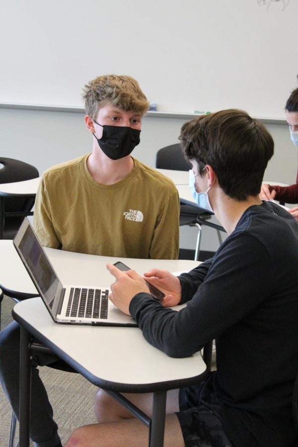 Junior Dylan Brewster talks to his classmate Charlie Graven while working on their finals. 