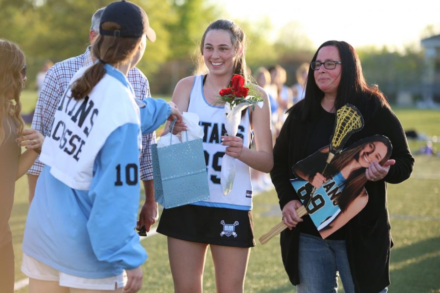 Being handed her gift, senior Avery Kotel gathers her items before posing for a photo with her parents and coaches on April 29. 