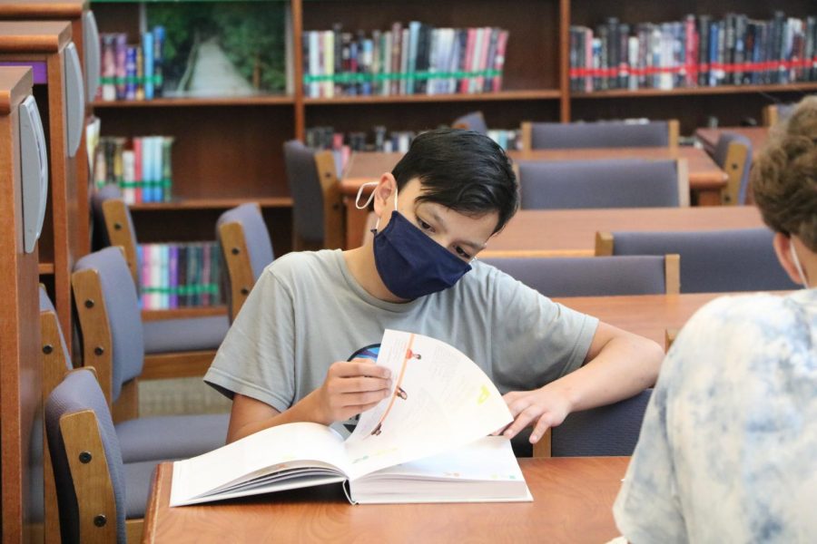 Looking through the pages, freshman Sean Quijano looks through this year’s yearbook on Distribution Day on May 19.