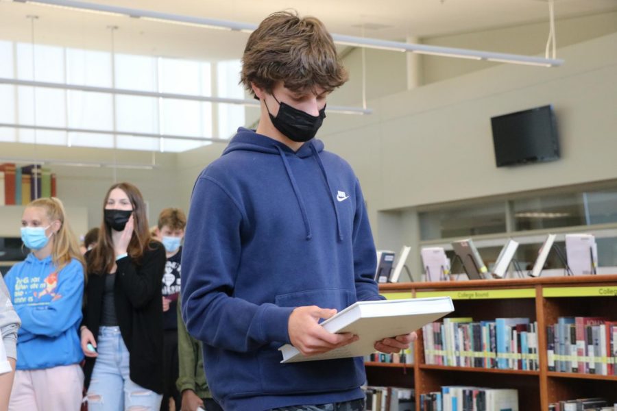 Looking down, freshman Kade Holmes collects his book on Distribution Day on May 19.