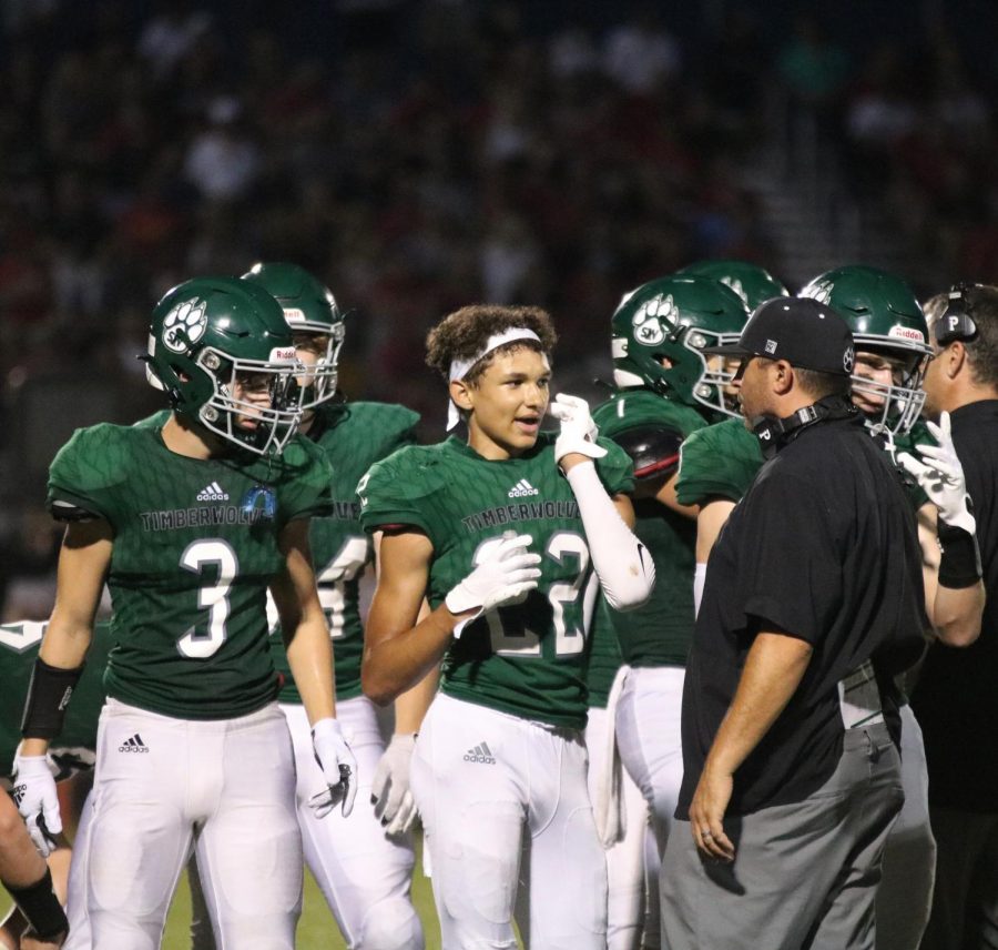 Sophomore Trey Thomas talks with a coach on the sideline during the senior night football game on Sept. 3.