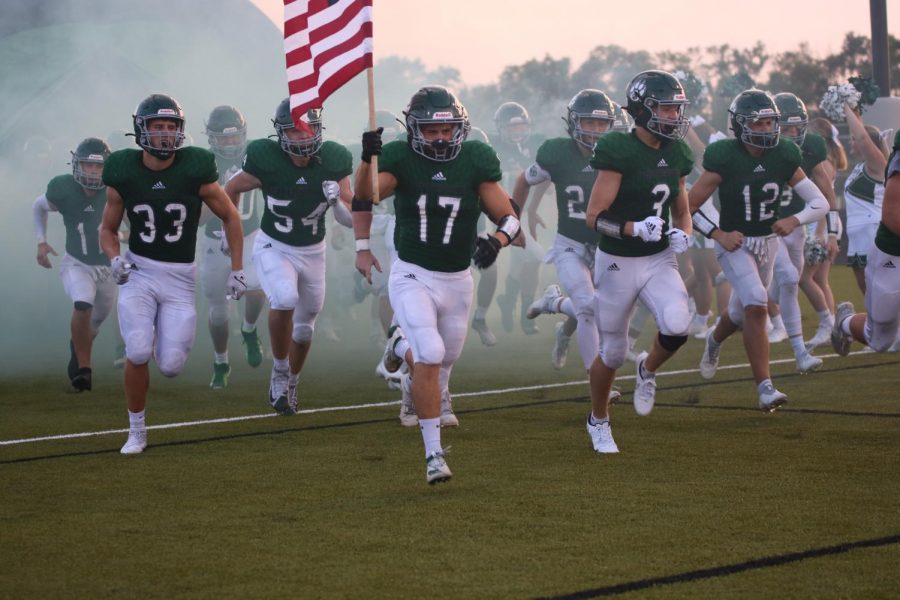 Senior Davis Brogan carries the flag out of the pregame tunnel at the Senior night football game on Sept.3.