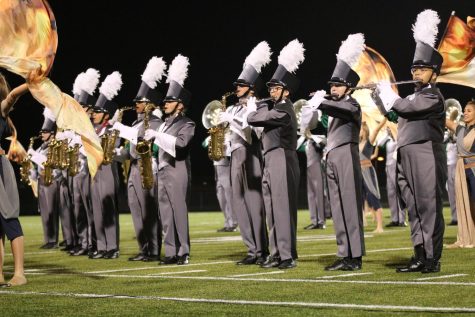 Standing in formation, freshman Bria Taylor (far right) plays alongside fellow members of the Emerald Regiment as they perform their 2021 field production “Babel” at halftime on Sept. 24. “Seeing everyone applaud us for working so hard has been my favorite,” Taylor said. “Everyone knows how hard we work and how much we rehearse.” Photo by Veronica Fuendling.