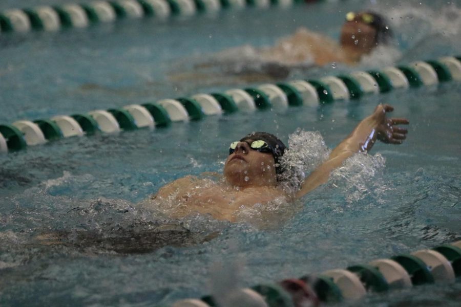 In his backstroke, junior Drew Christmann competes in the boys swim EKL on Feb. 4. “I thought we had a great season,” Christmann said, “we had a lot of new swimmers qualify for state and break a few records.” The swim team placed 5th overall in state on Feb 19. Photo by Lena Palmieri. 
