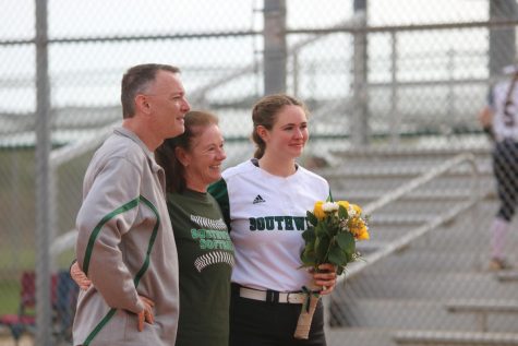 Flowers in hand, senior Tori Woodard celebrates her senior night with her parents on April 25. 