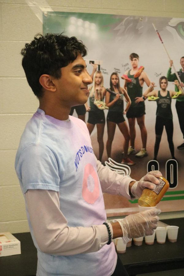 Sophomore Darsh Patel pours sauce for his food into a cup. 