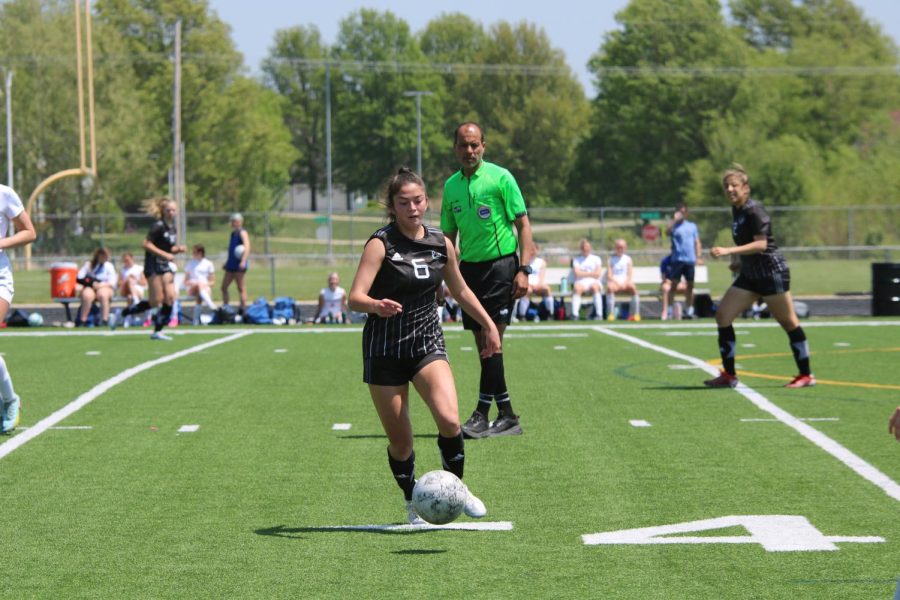 Gaining possession and dribbling the ball, sophomore Sadie Sant leans forward. 