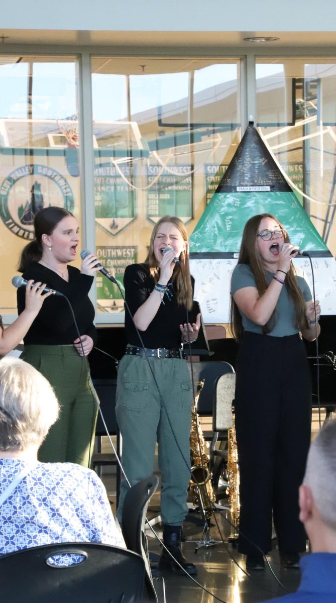 Hitting the notes, junior Emily Chipak along with juniors Libby Davis and Alivia Carmichael sing in a semicricle to songs on Apr. 11 during the Jazz Cafe. There were multiple songs each group preformed throughout the night.