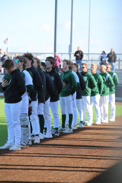 In the center, senior Sterling Widman holds his hat to his chest on April 3. Widman stood with the varsity baseball team for the national anthem.