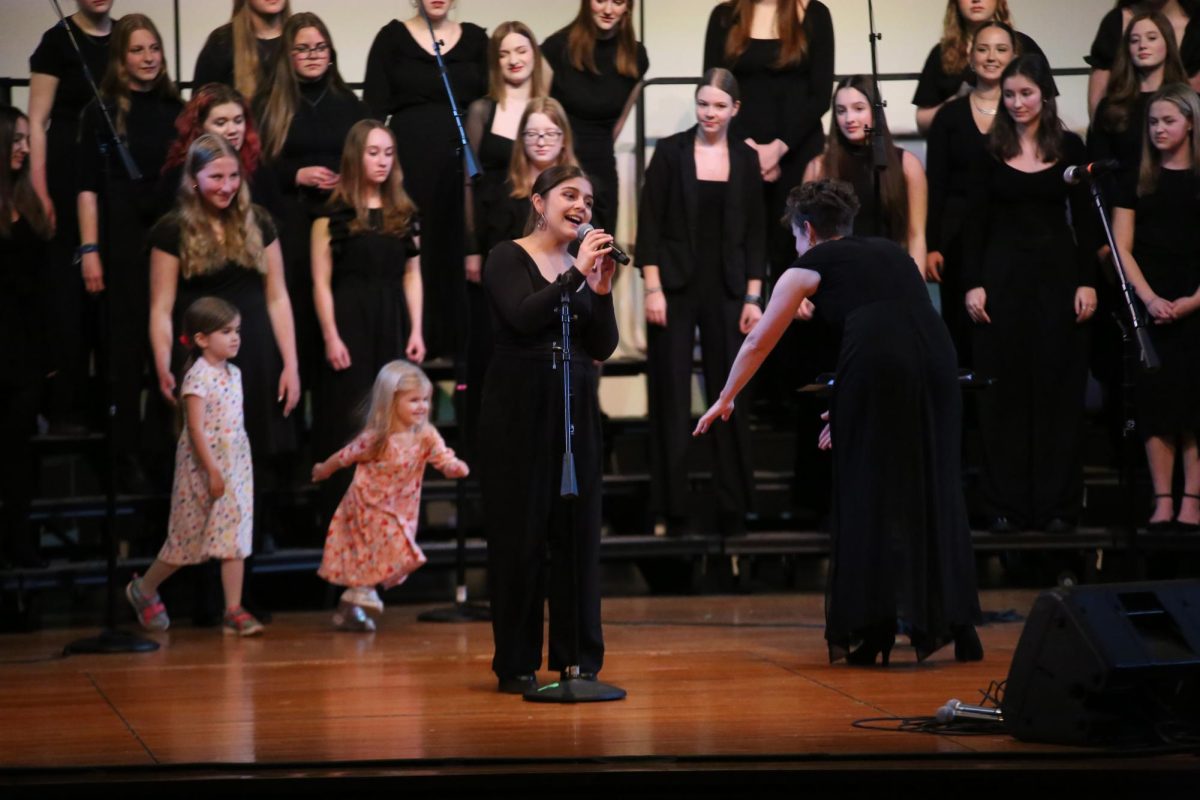 Emotion on her face, senior Mia Cabrera Davila stands at the mic stand to perform her solo during the choir concert on March 21. Prior to the last song, choir teacher Taryn Gervais brought her kids to the stage to sing the beginning of the song.