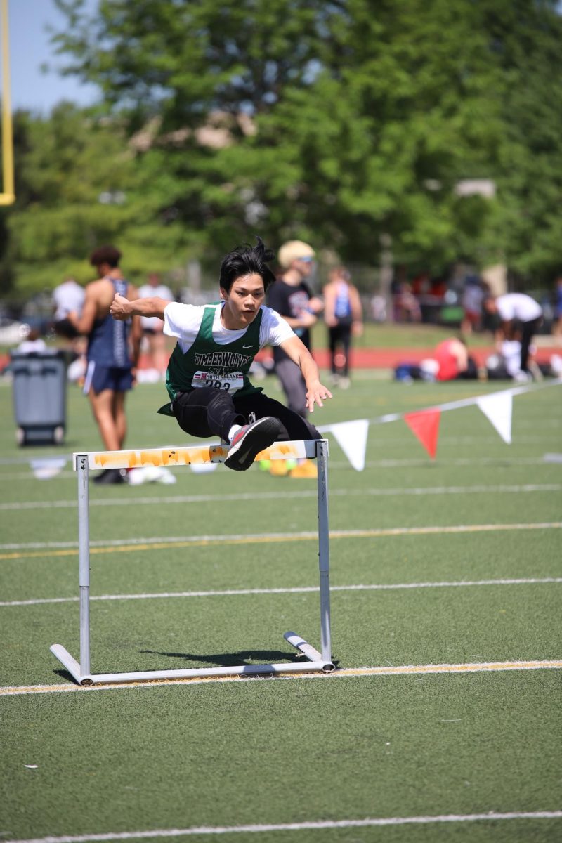 In the air, sophomore John Lee flies over the hurdle on May 3.
