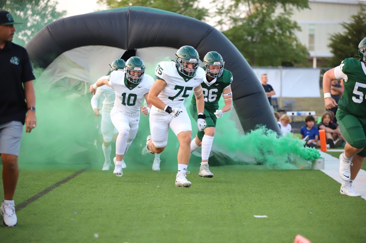 Seniors Ryan Specht, Jackson McCarty and Quinn Lemons run out of the tunnel on Aug. 8 at the Green and White football scrimmage.