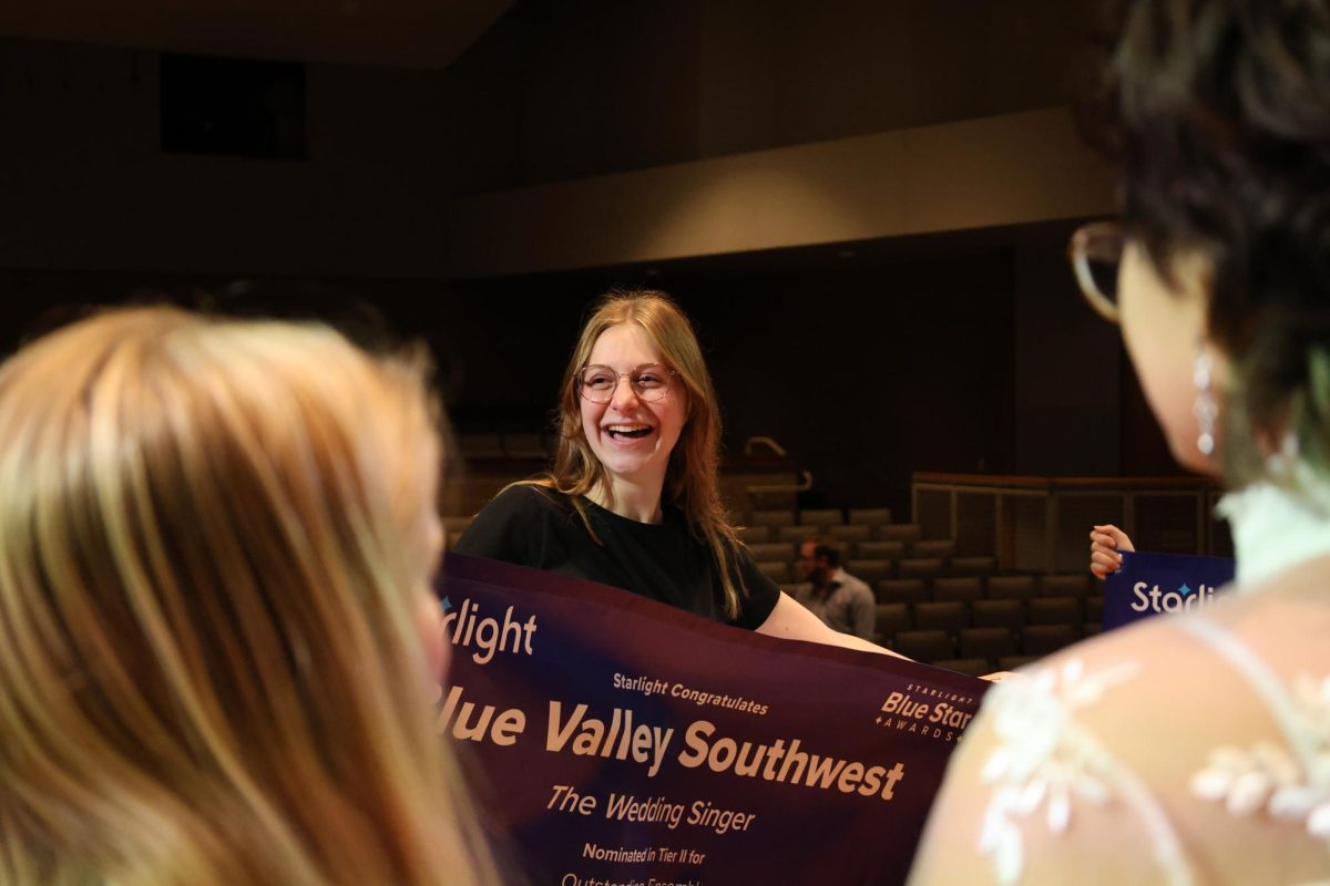 Senior Emily Chipak smiles big while holding the banner. 