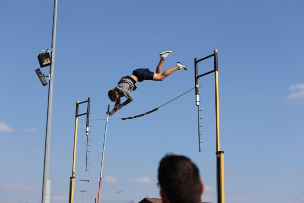 In the air, junior Dylan Cross jumps over the bar while pole vaulting at a track meet at Blue Valley High on April 11.