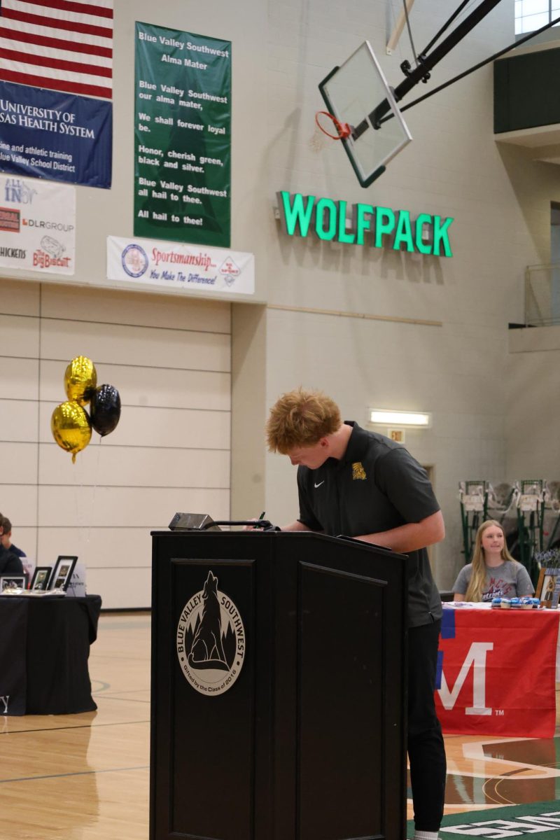 Up at the stand, Senior Ryan Specht signs the paper for signing day