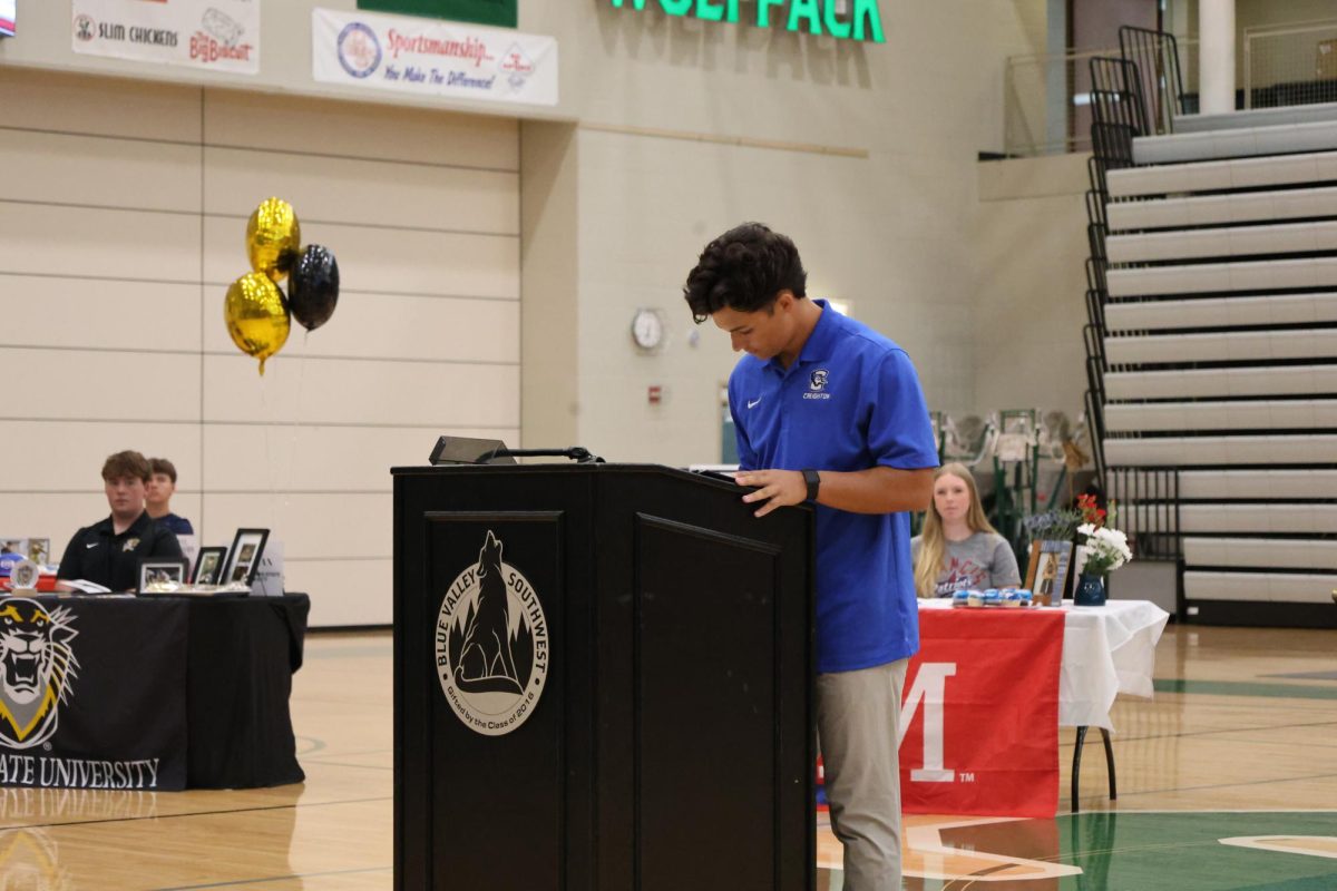 In blue, senior Brody Shinkle prepares to write his name on the signing day paper