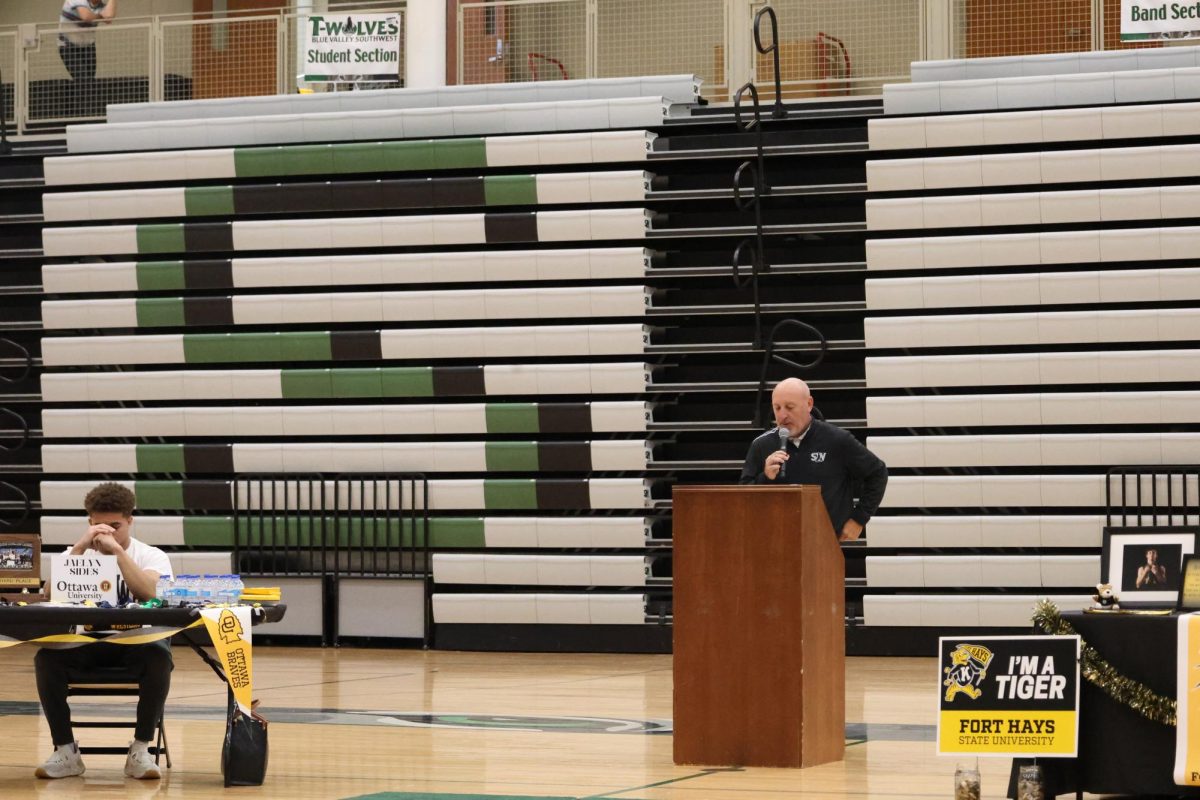 Microphone in hand, athletic director Mike Rasmussen gives a speech before the seniors sign
