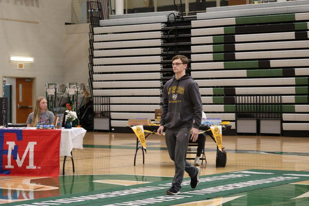 Walking, senior Kaden Markley walks and prepares to sign the papers
