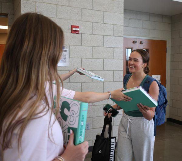 Hand on yearbook, junior Arden Harms receives her yearbook from a publications staff member at distribution day on May 9.