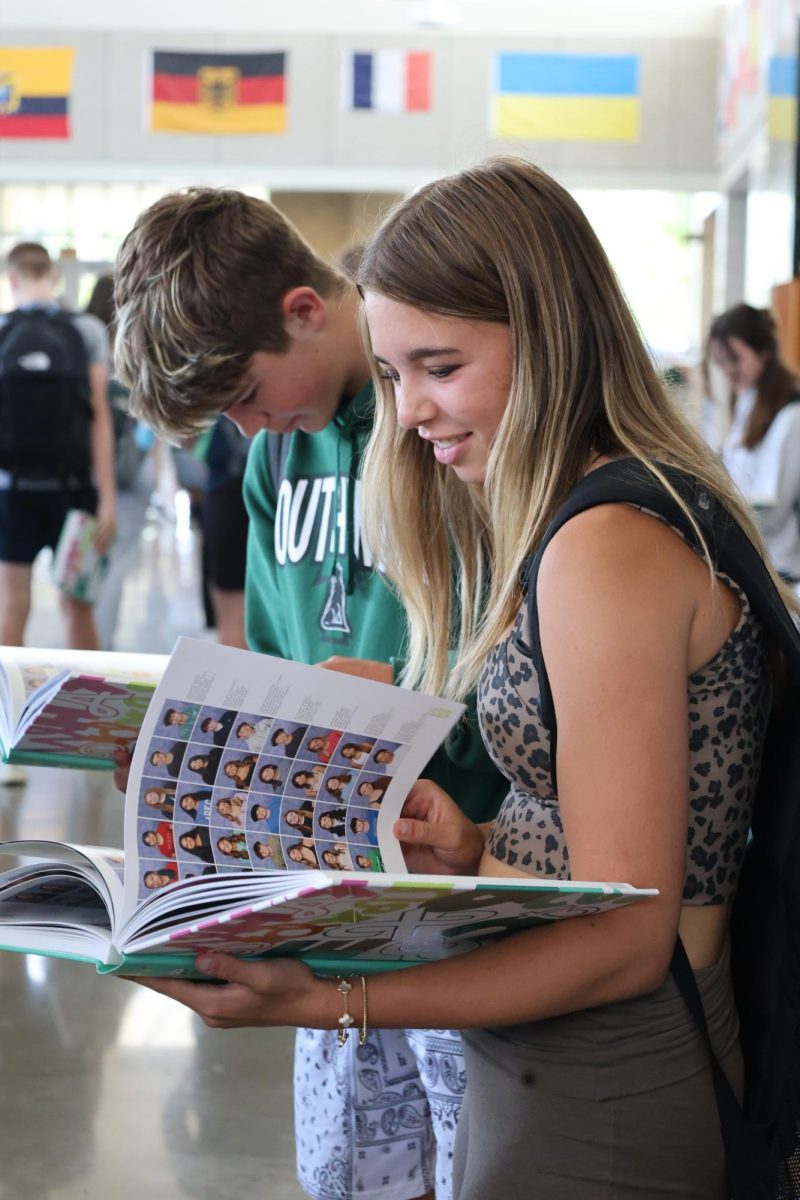 Flipping the pages, freshman Sophia Kramer looks back on moments throughout the school year on May 9 on yearbook distribution day.
