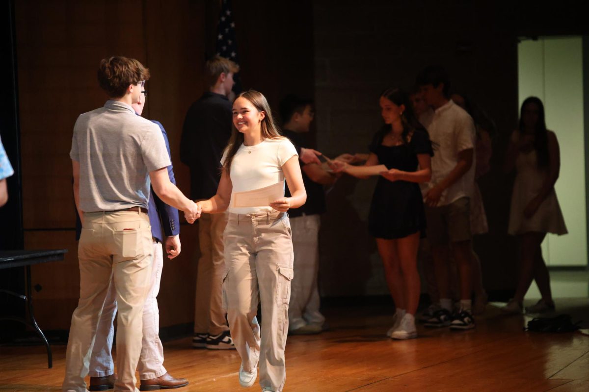 Junior Arden Harms shakes hands as she receives her certificate and walks across the stage