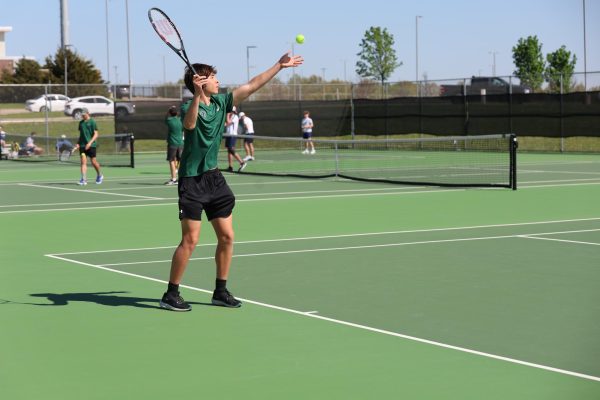 On April 21st, sophmore Nicholas Heinen serves the ball to his opponent during a JV doubles match against St. Thomas Aquinas