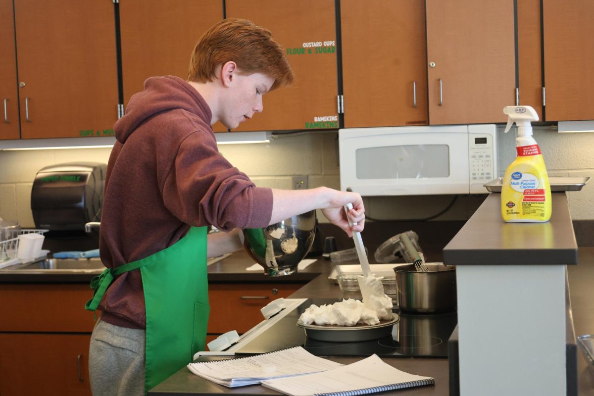 Locked in, junior Levi Oestreich spreads whipped cream on his pie during Baking and Pastry on Oct. 23.