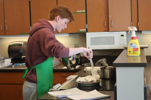 Locked in, junior Levi Oestreich spreads whipped cream on his pie during Baking and Pastry on Oct. 23.