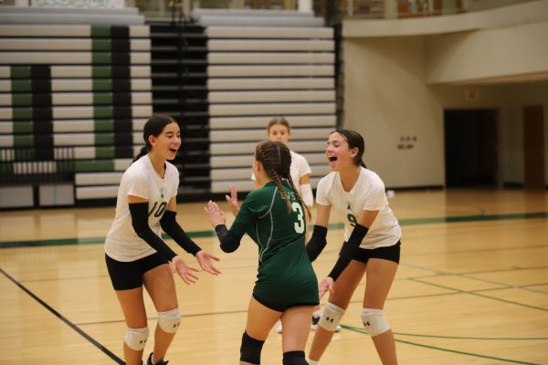 Celebrating after a point, freshmen Etta Scalise, Olivia Hutchinson and Rachel Heinrich give each other high fives on Oct. 8.